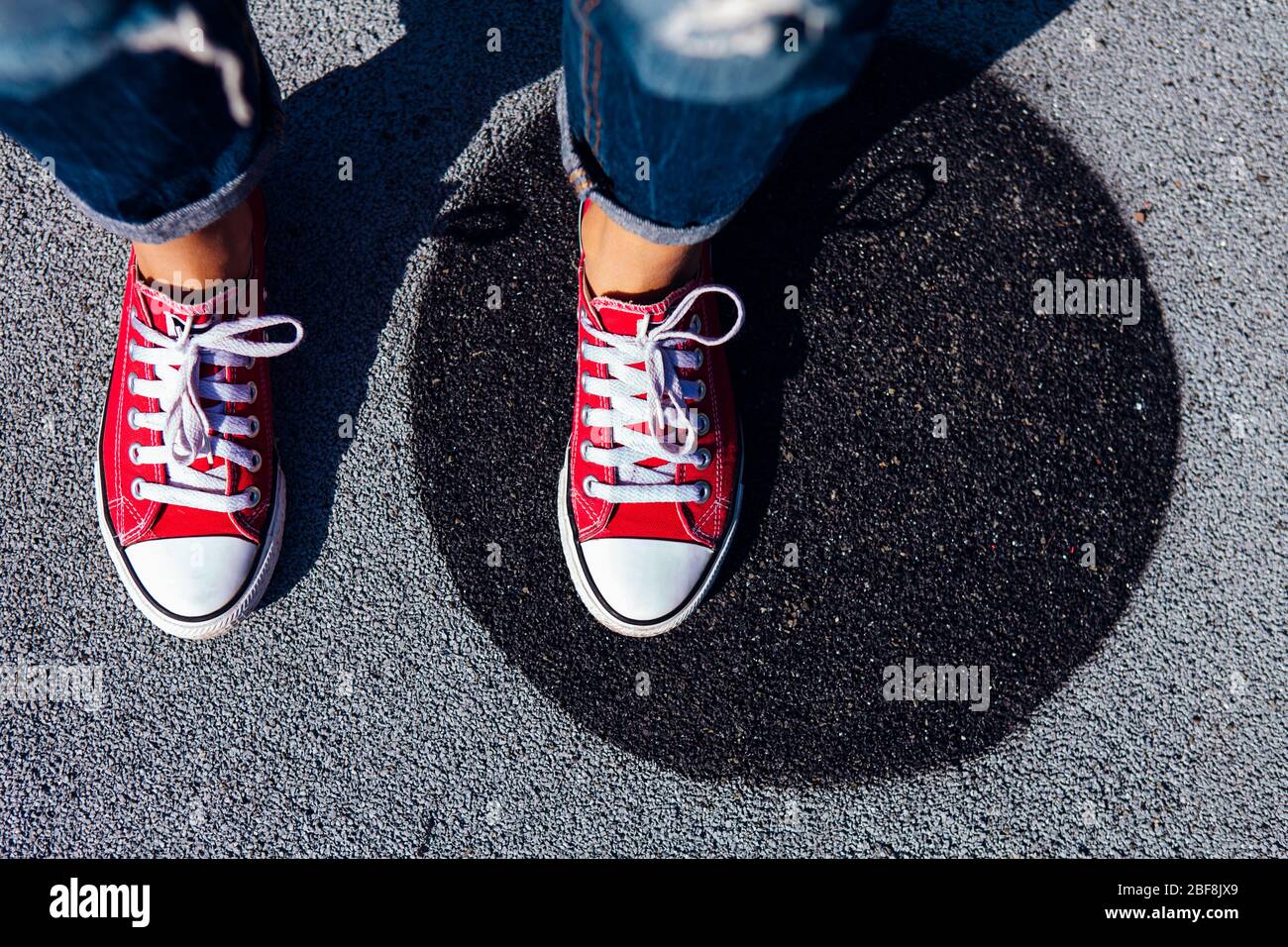 Red canvas sneakers shoes on woman's feet on the asphalt with black ...