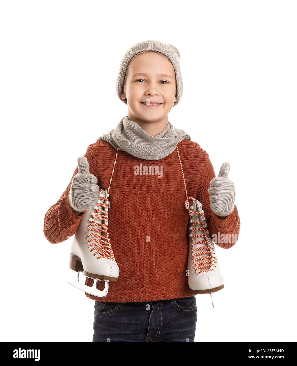 Cute little boy with ice skates showing thumbup against white
