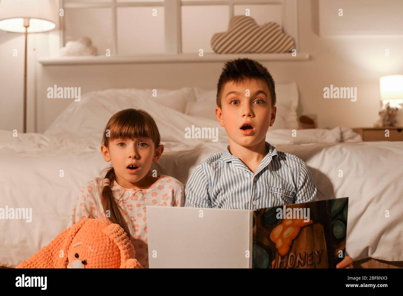 Scared little children reading bedtime story at home Stock Photo