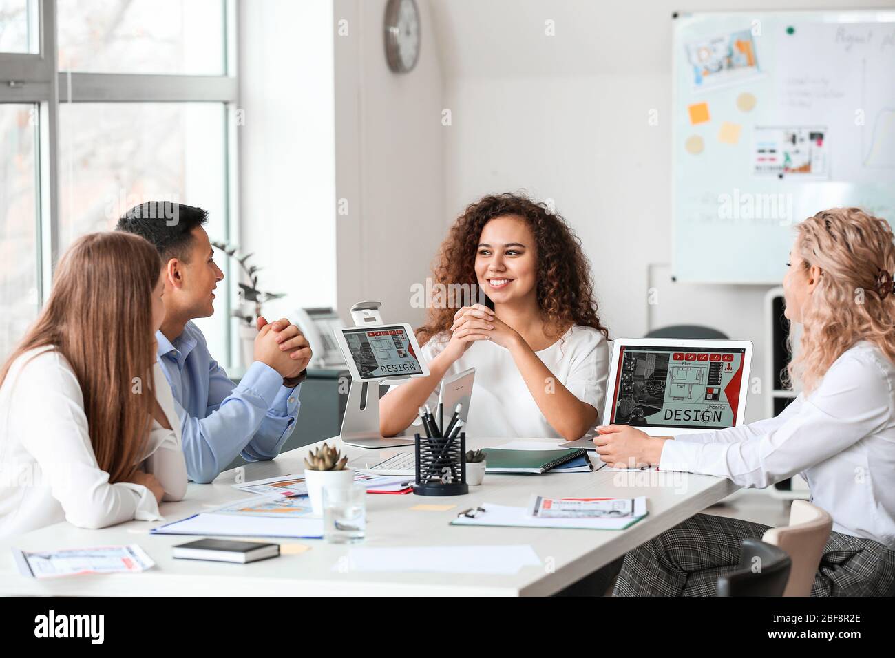 Female interior designer teaching young people in office Stock Photo ...