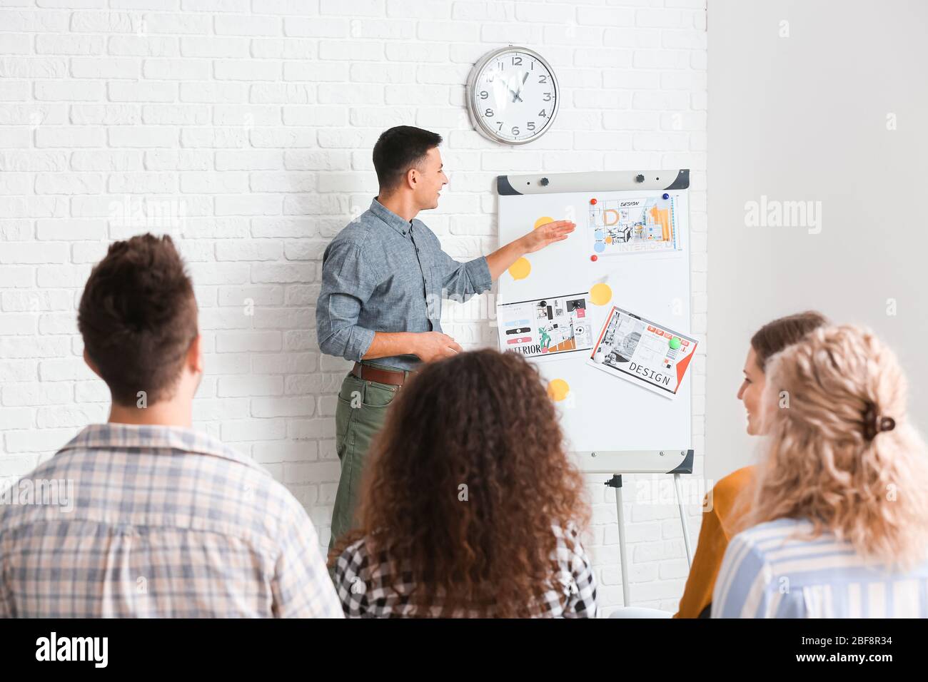 Male interior designer teaching young people in office Stock Photo - Alamy