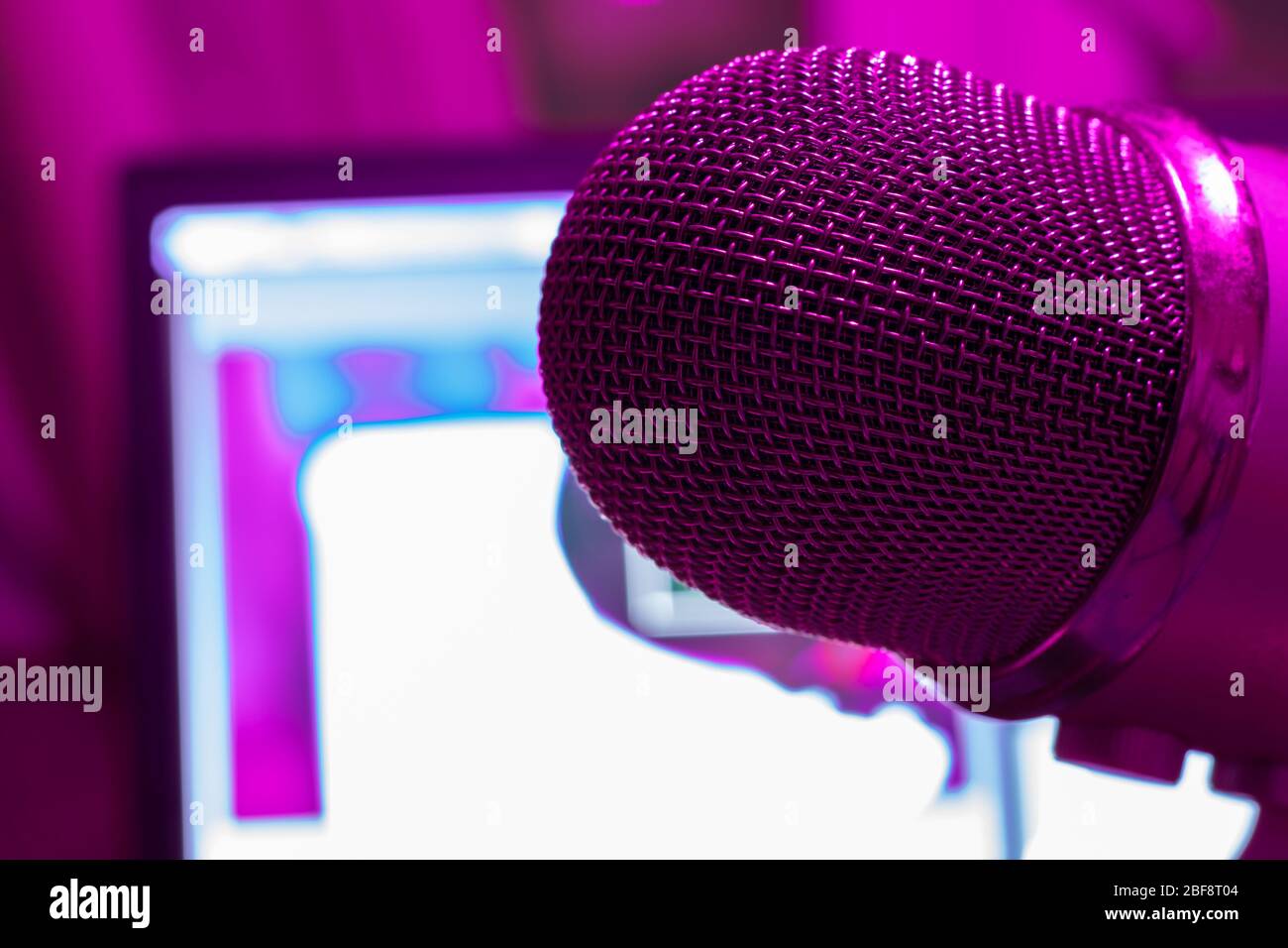 Pro microphone for broadcast with laptop on background in purple light. Podcast studio with copy space Stock Photo