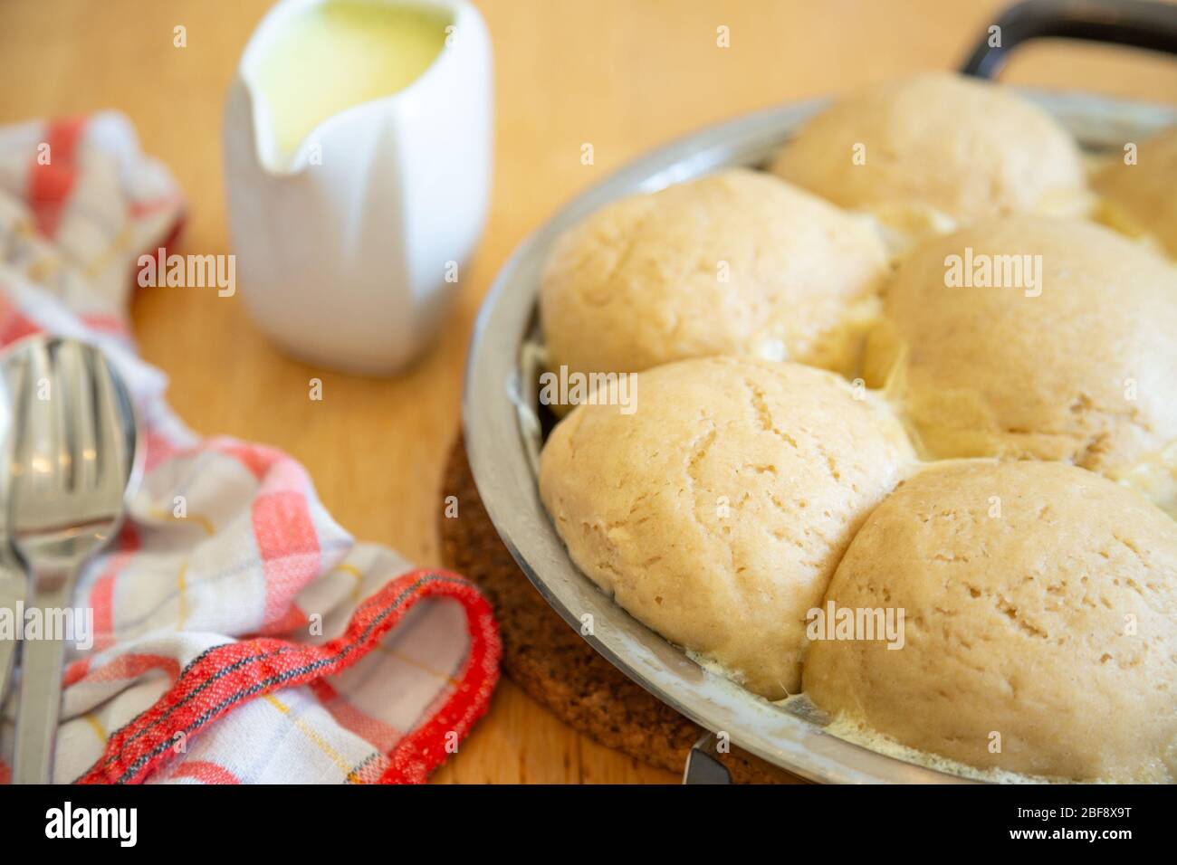 Traditional fresh bavarian yeast dumplings, vegan version, served with vanilla sauce in a pan Stock Photo