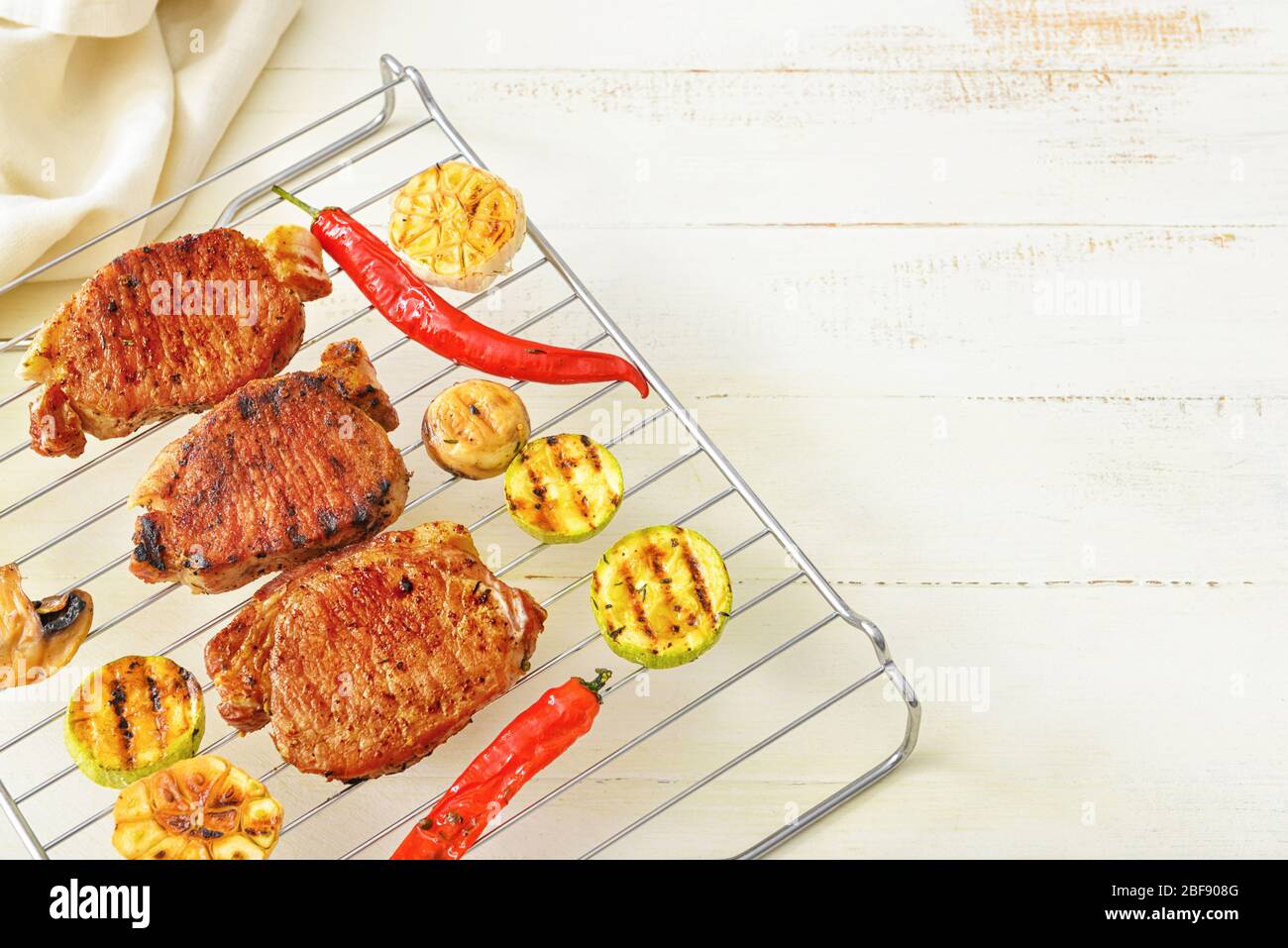 Cooked On Rack Cooling rack with cooked pork steaks and vegetables on table Stock ...