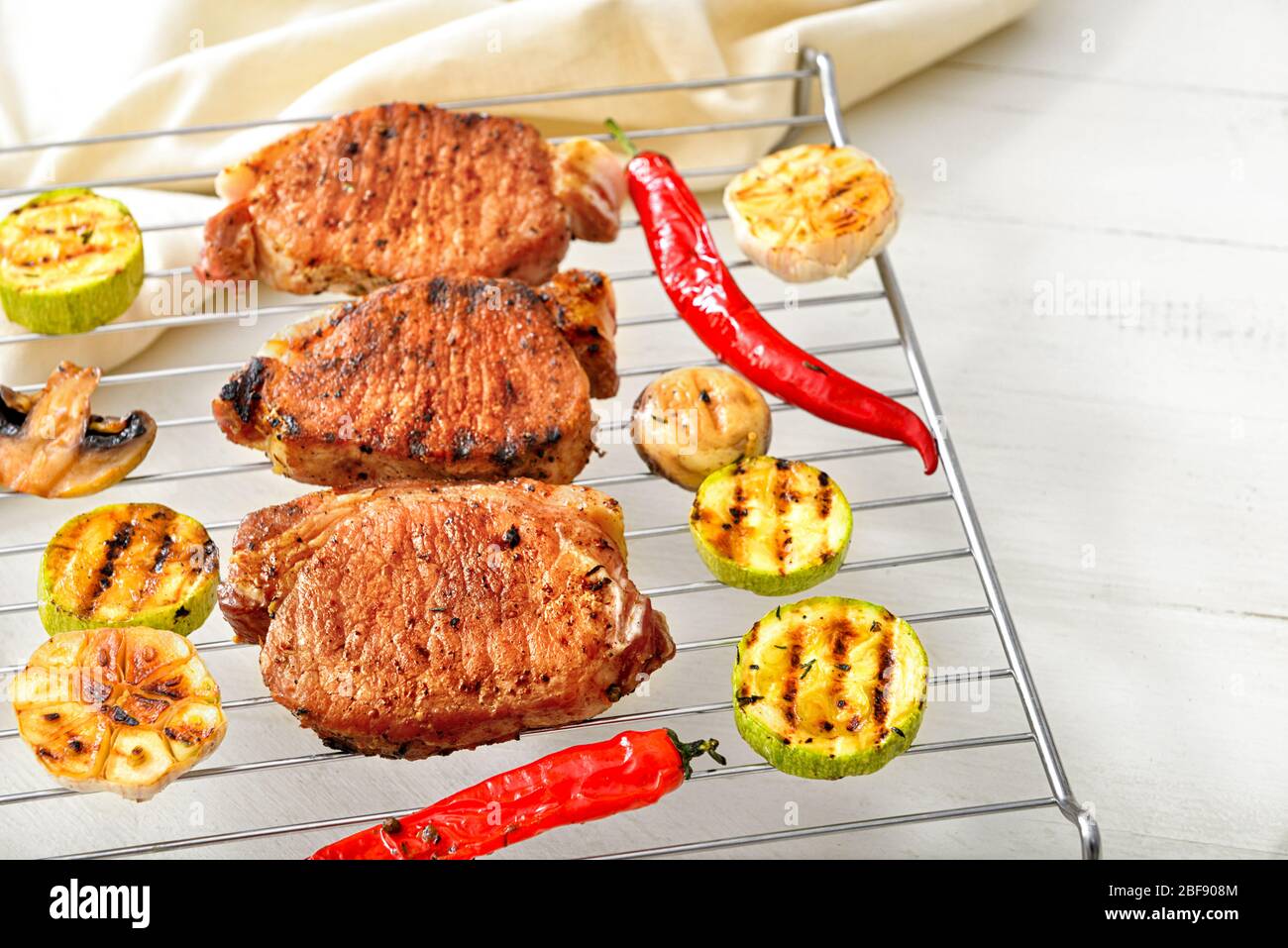 Cooked On Rack Cooling rack with cooked pork steaks and vegetables on table Stock ...