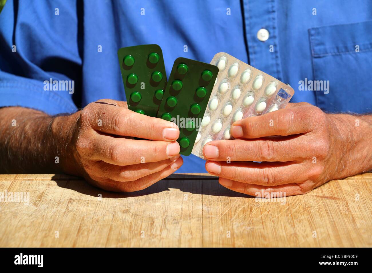 Man with a blue shirt holding pills and tablets Stock Photo