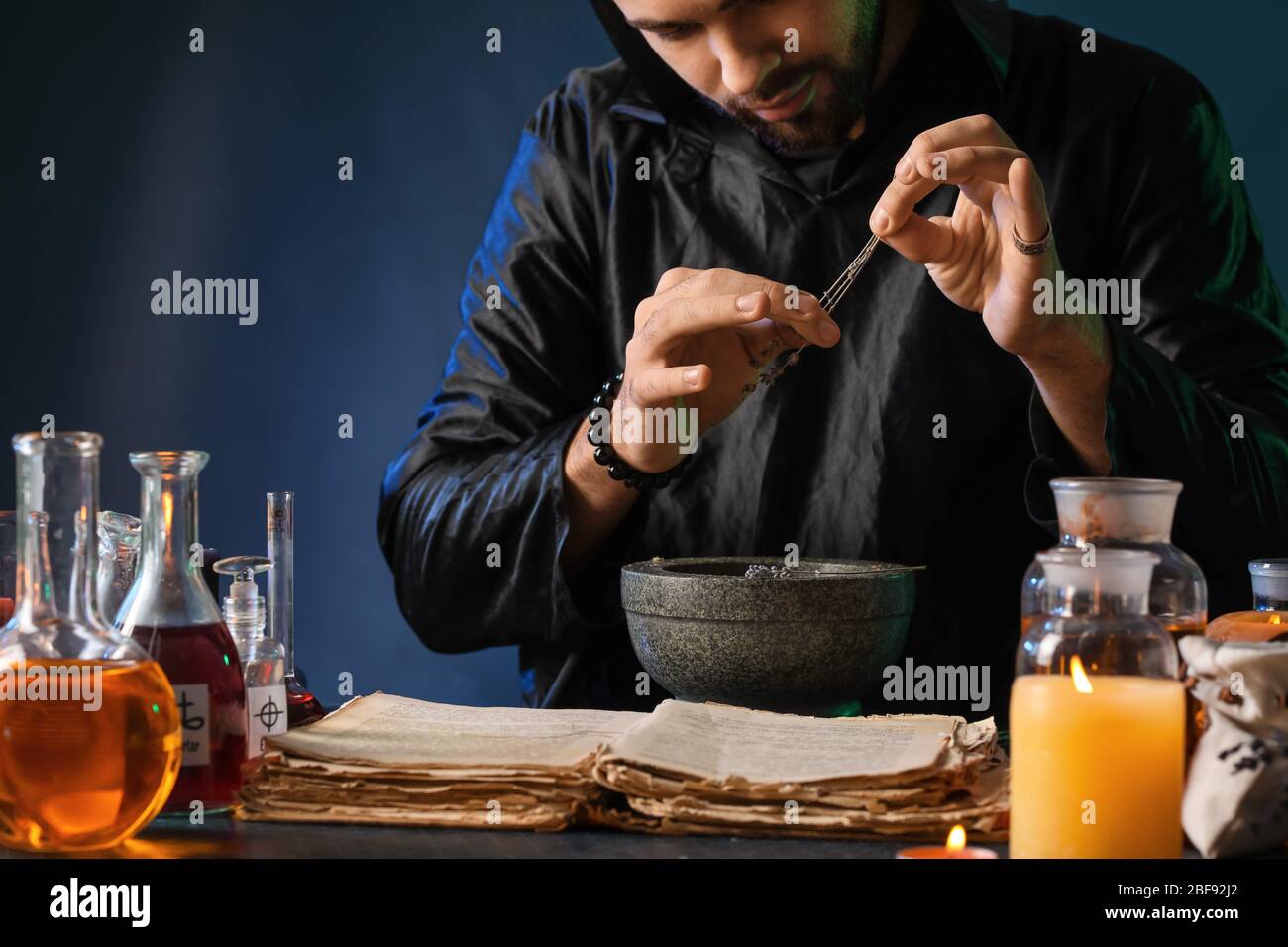 Male alchemist making potion on dark background Stock Photo