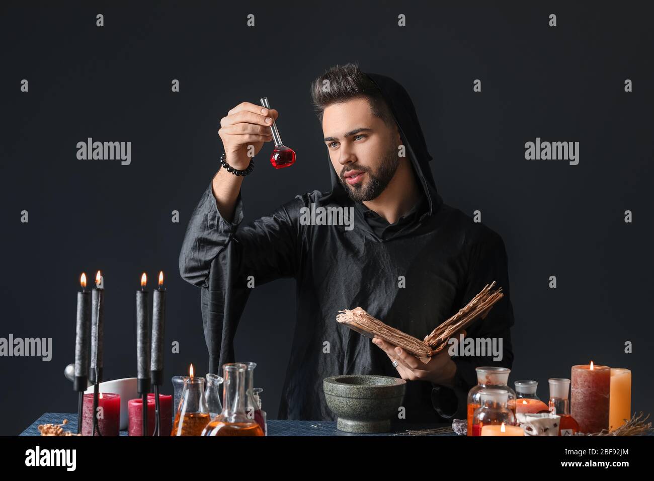 Male alchemist making potion on dark background Stock Photo