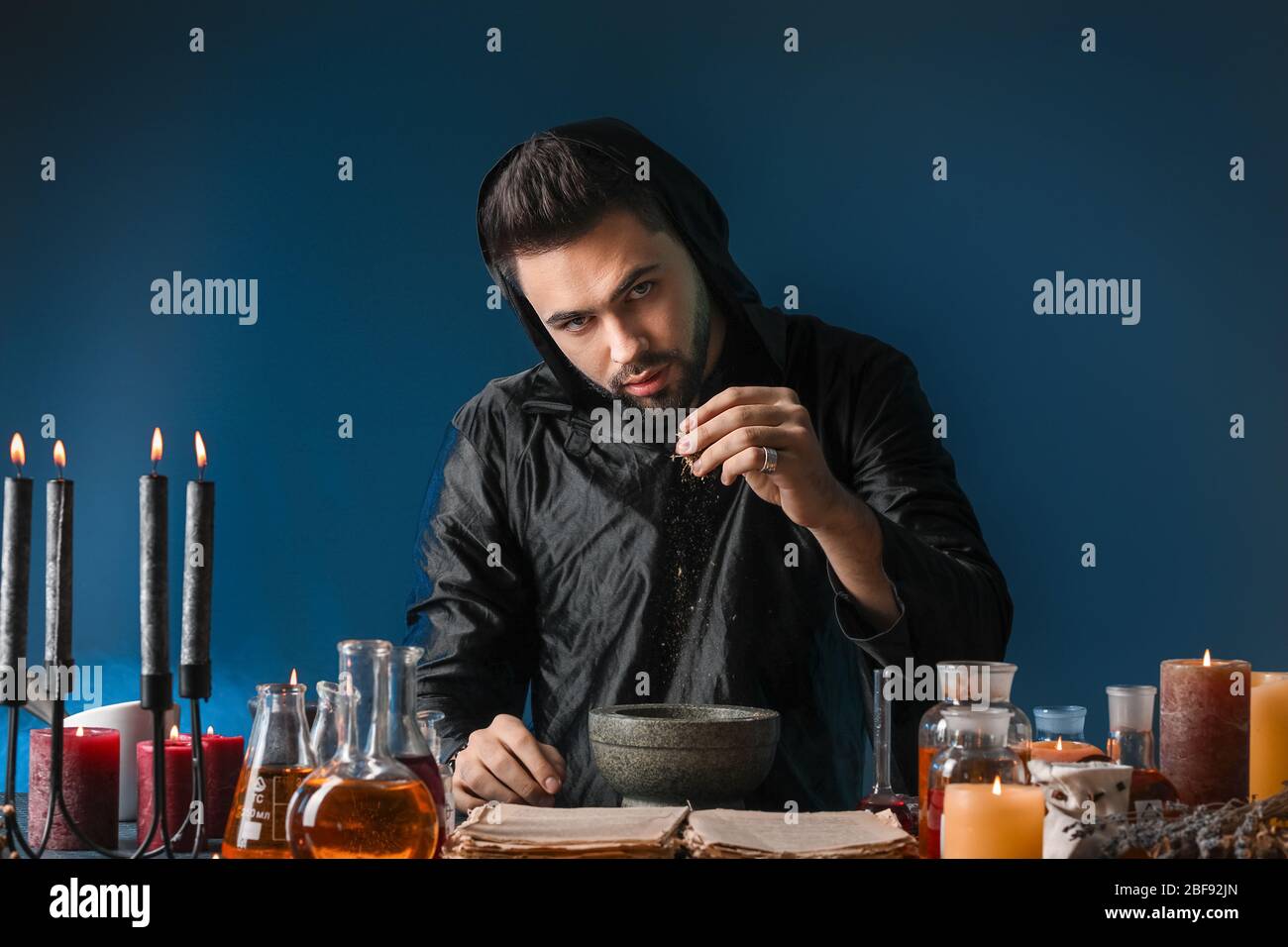 Male alchemist making potion on dark background Stock Photo