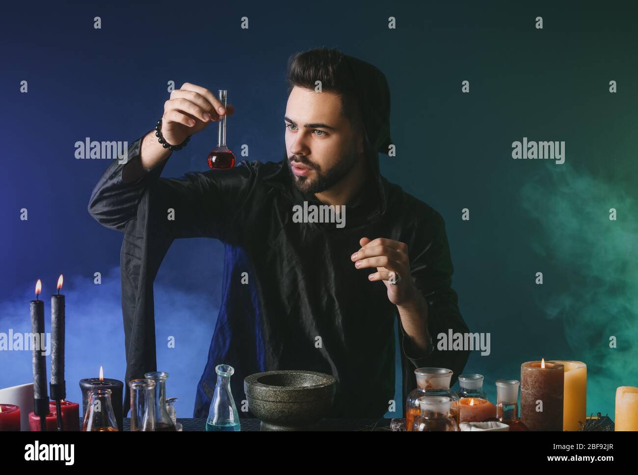 Male alchemist making potion on dark background Stock Photo