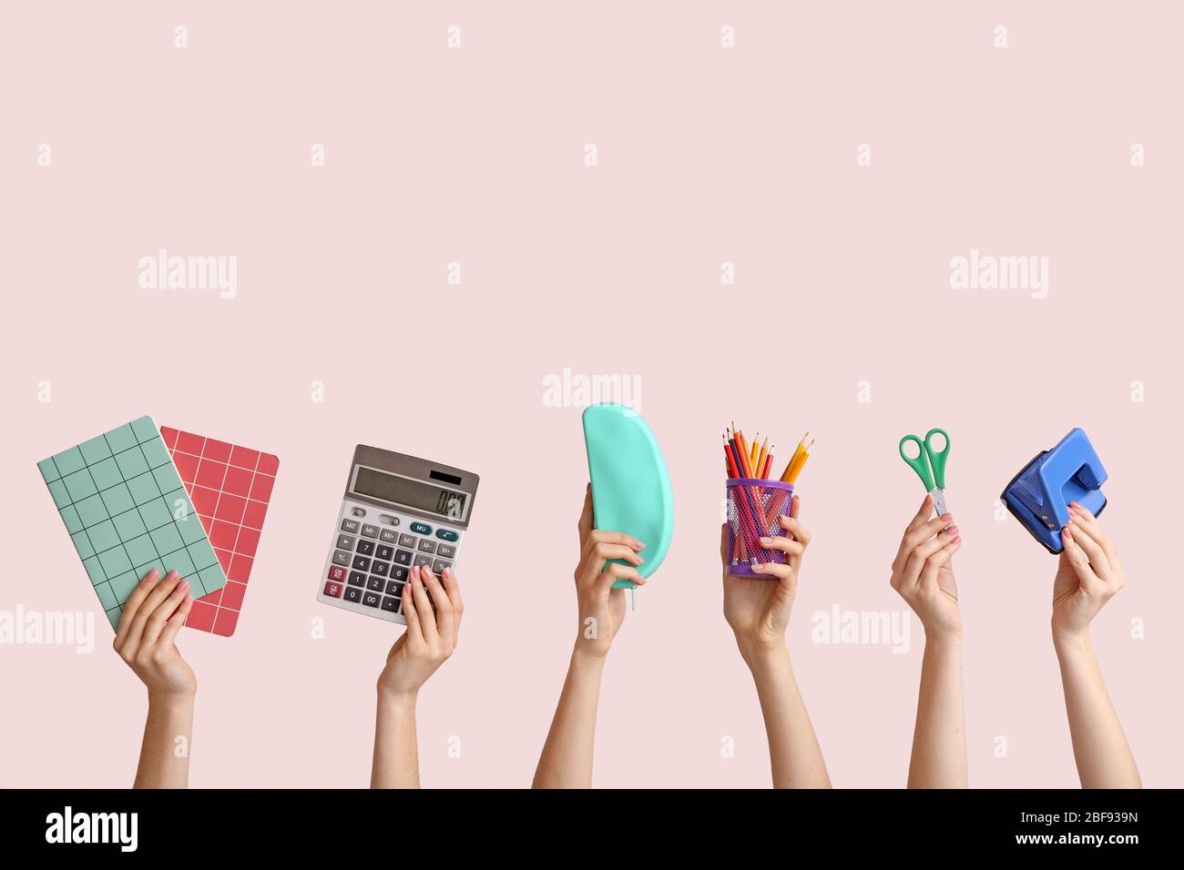 Many hands with school supplies on light background Stock Photo - Alamy