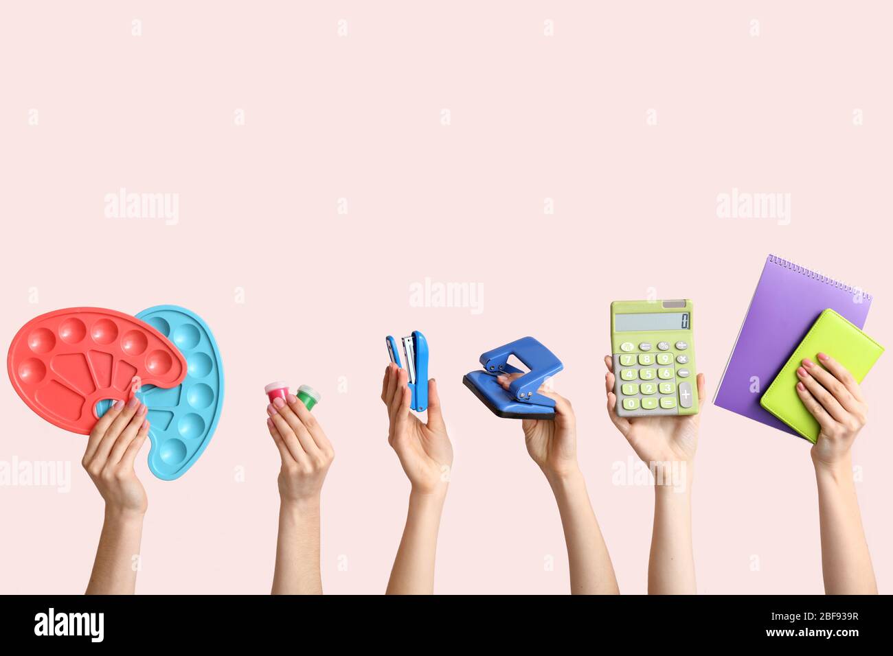 Many hands with school supplies on light background Stock Photo - Alamy