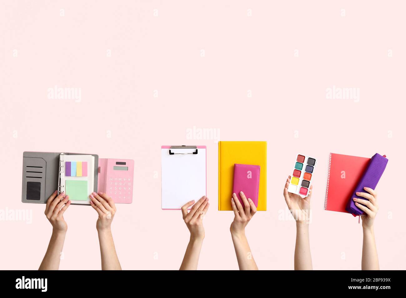 Many hands with school supplies on light background Stock Photo - Alamy