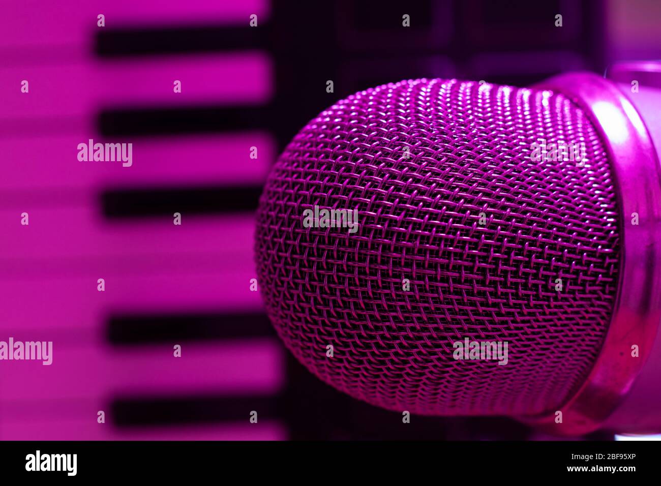 Above shot of condenser microphone with synthesizer keyboard for music production making. Purple light Stock Photo