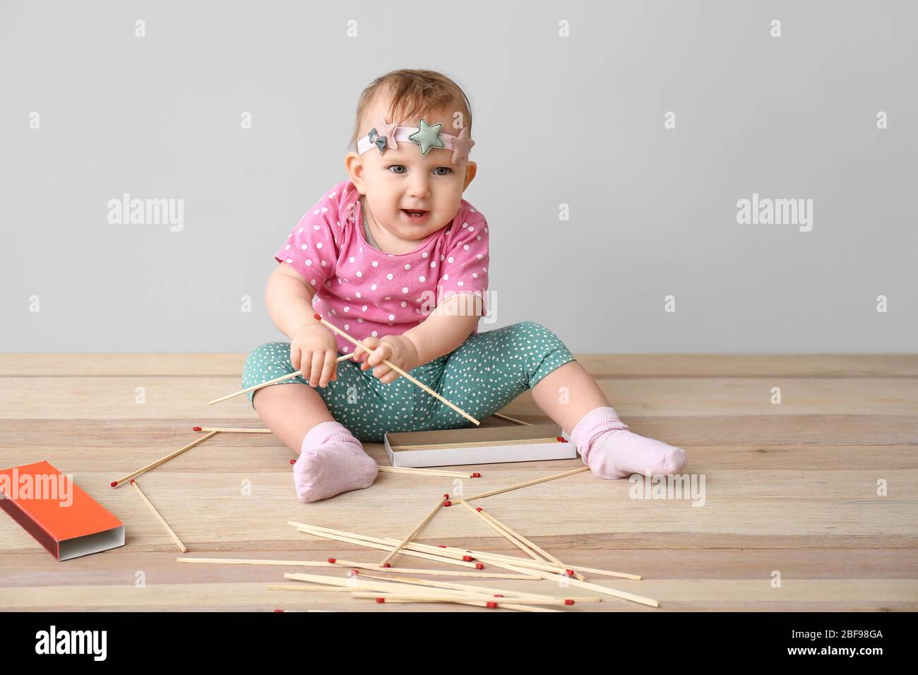 Little baby playing with matches while sitting on table. Child in danger Stock Photo