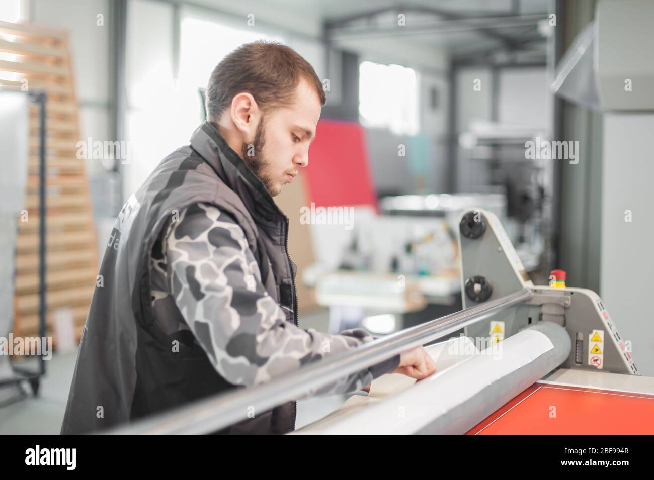 Worker printmaker technician glue large paper poster to foam board with