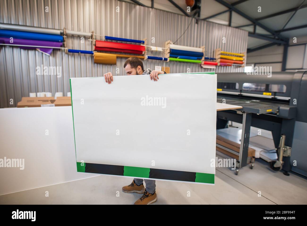 Worker printmaker technician operator works in large digital printing