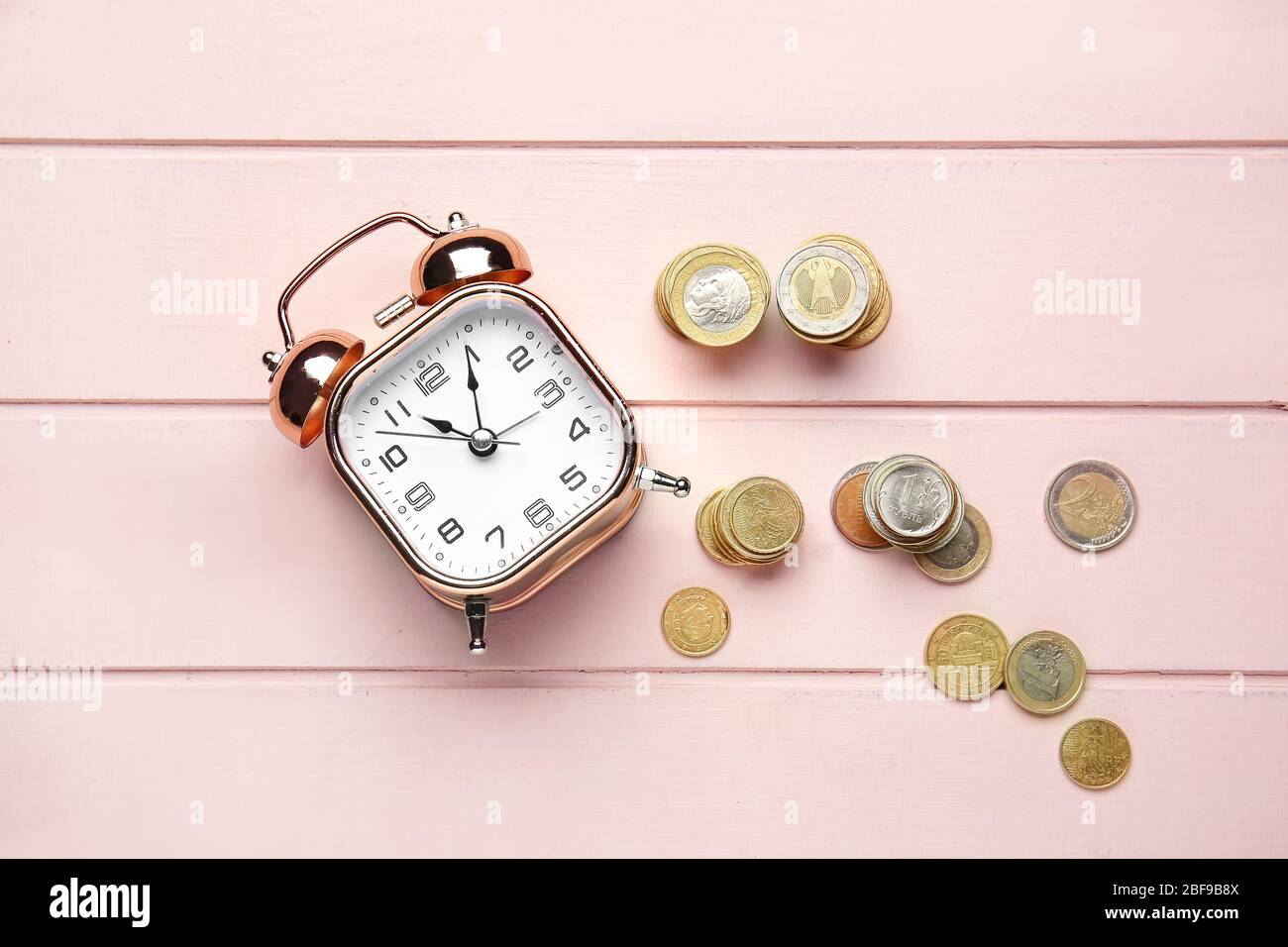 Alarm clock and coins on wooden table. Time management concept Stock Photo