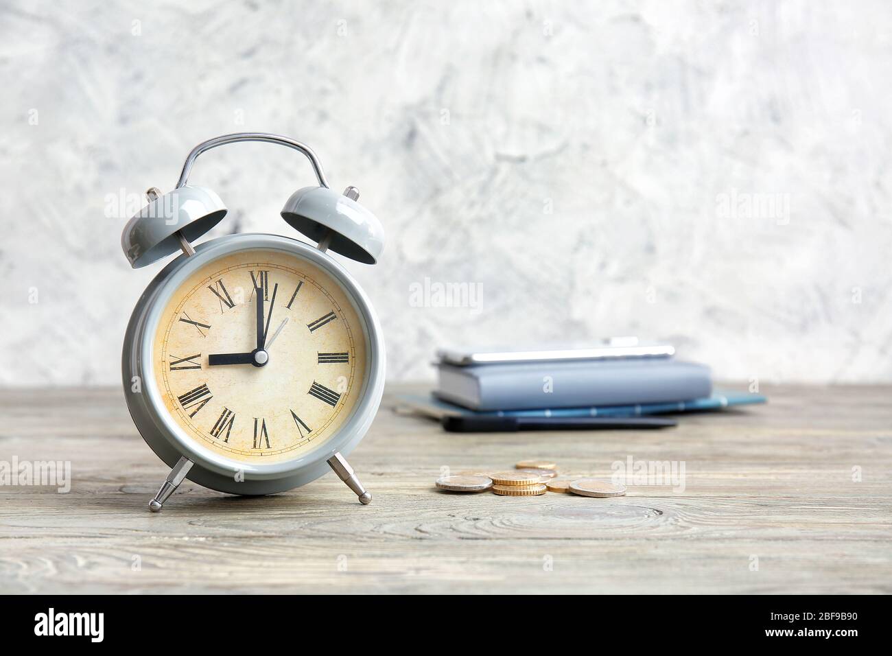 Alarm clock and coins on wooden table. Time management concept Stock Photo