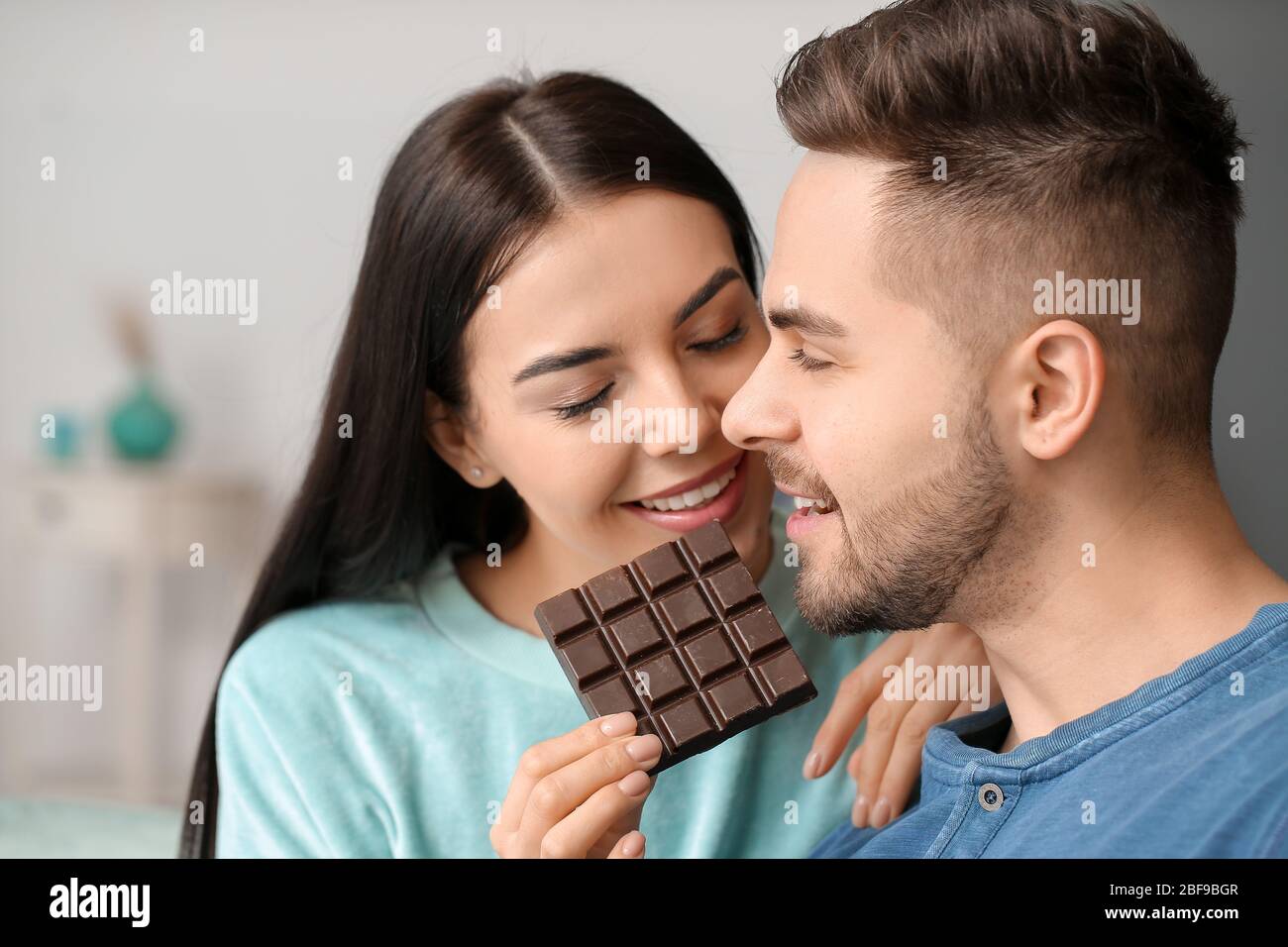 Beautiful young couple eating chocolate at home Stock Photo - Alamy