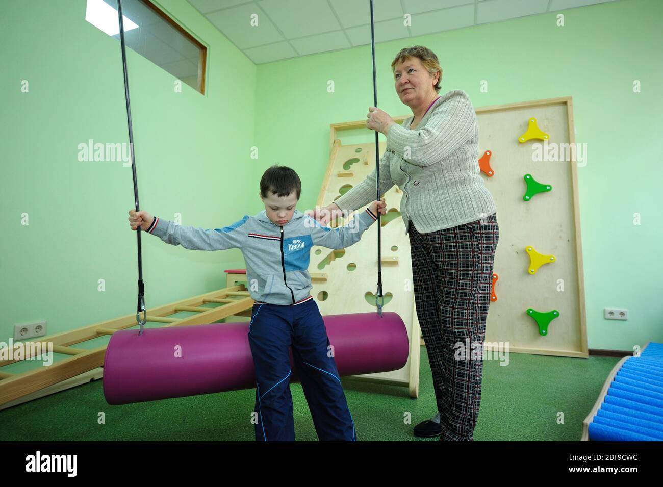 Improving motor control female therapist helping Down syndrome boy to