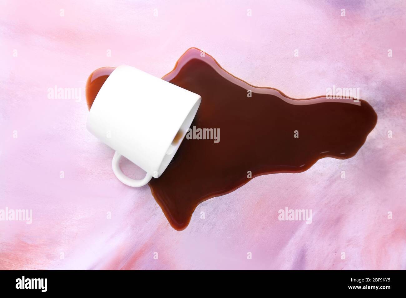 Overturned cup and spilled coffee on table Stock Photo