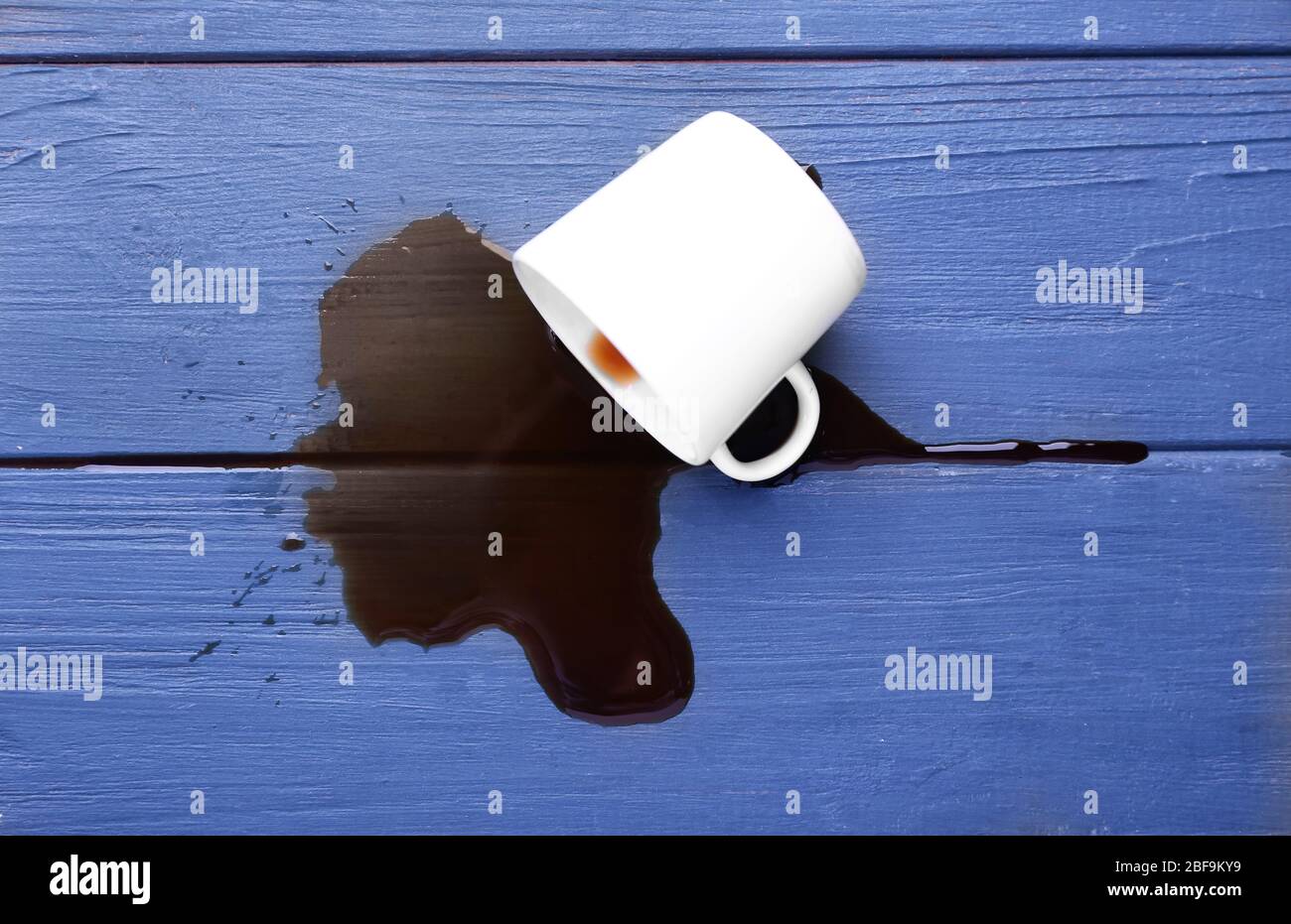 Overturned cup and spilled coffee on table Stock Photo