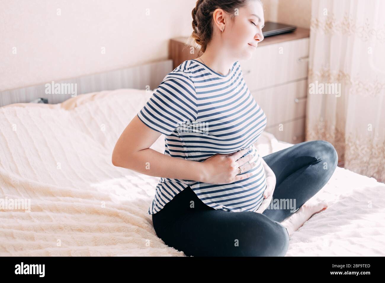 Close-up, Belly Of A Pregnant Young Girl Who Wears A Pink Sweater, Holds  White Headphones On Her Belly, The Baby Listens To Music. The Concept Of  Pregnancy, Motherhood, Preparation And Expectation. Stock