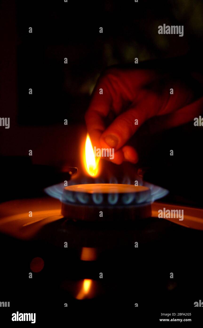 a man lighting a gas cooker ring by match Stock Photo Alamy