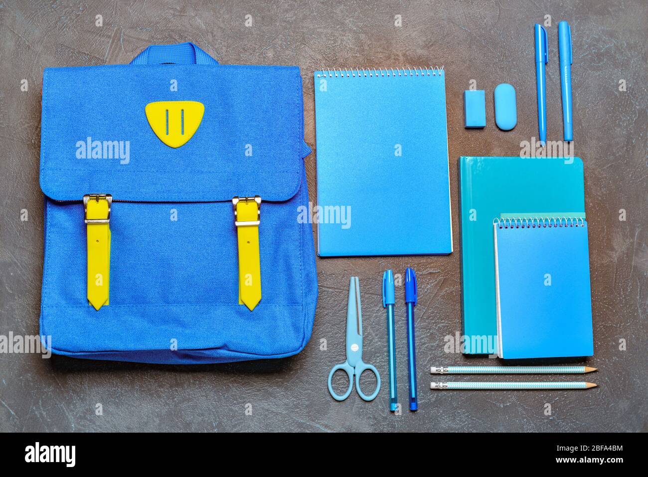 School backpack and stationery on grey background Stock Photo