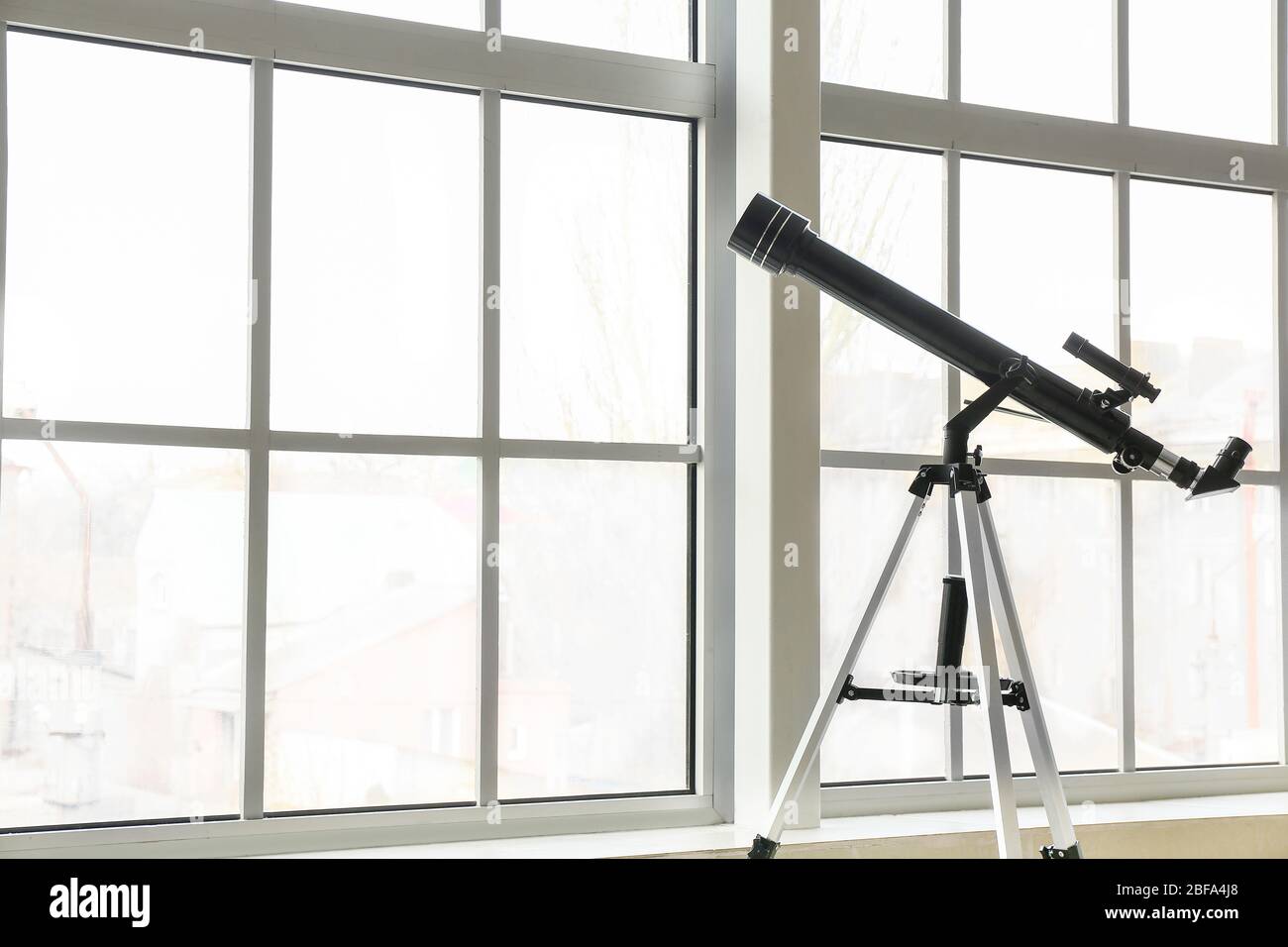 Modern telescope near window in room Stock Photo - Alamy