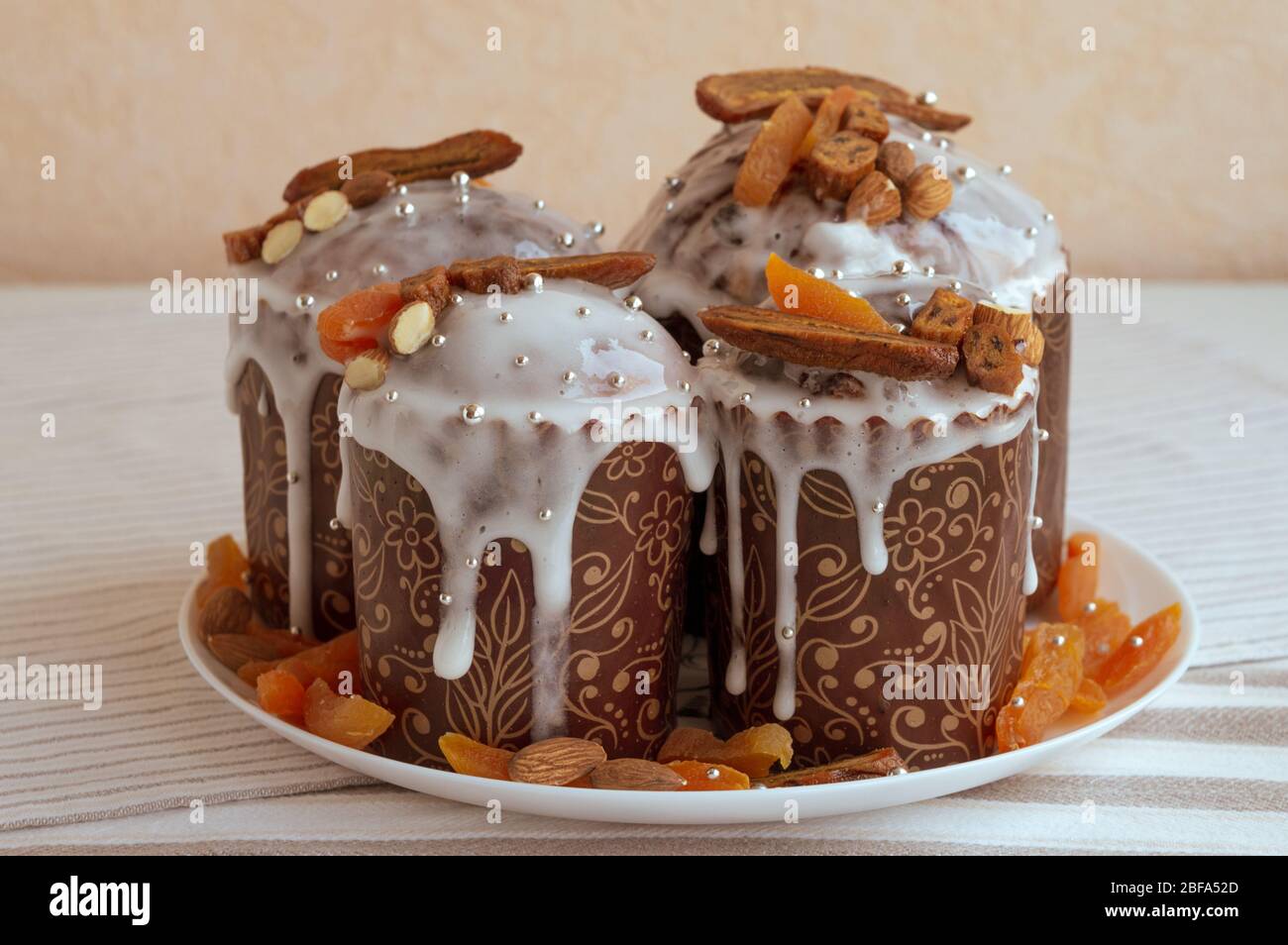 Four Easter cakes at the middle decorated by dried bananas, orange apricots, almonds and small elegant sugar silver pearl beads. Stylish trendy concep Stock Photo