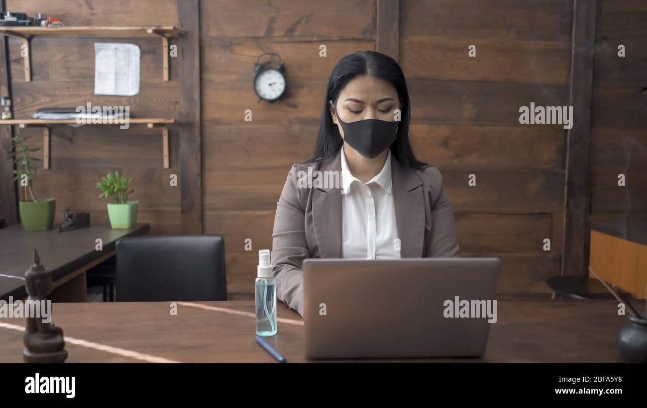 Oriental Woman Works Alone On Laptop In Office Interior Stock Photo