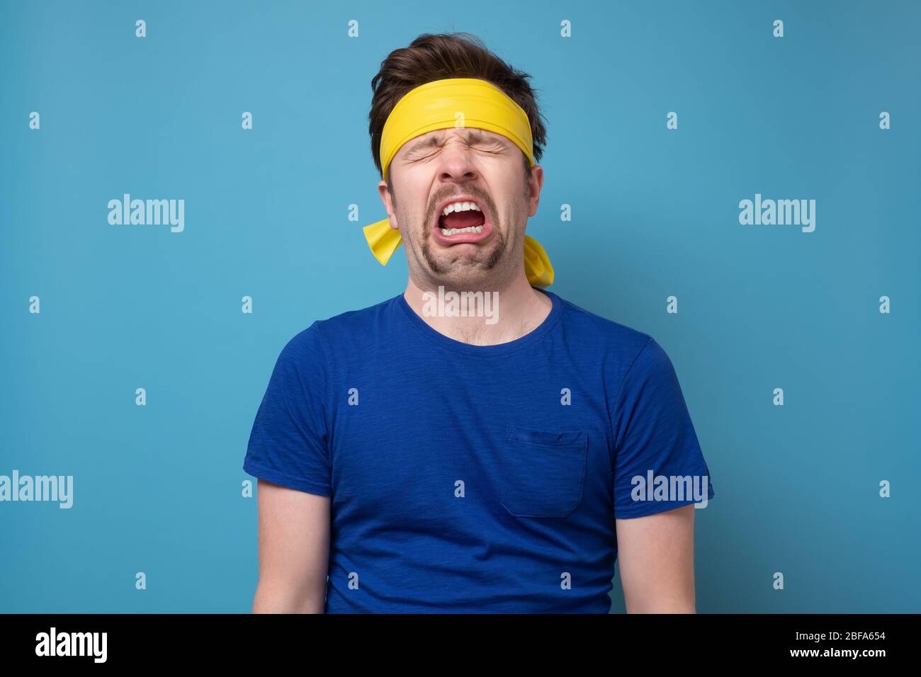 Young caucasian sport man with yellow rubber band whining and crying disconsolately Stock Photo