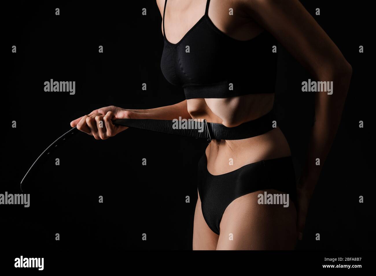 Sick woman tightening her waist with belt on dark background. Concept of  anorexia Stock Photo - Alamy