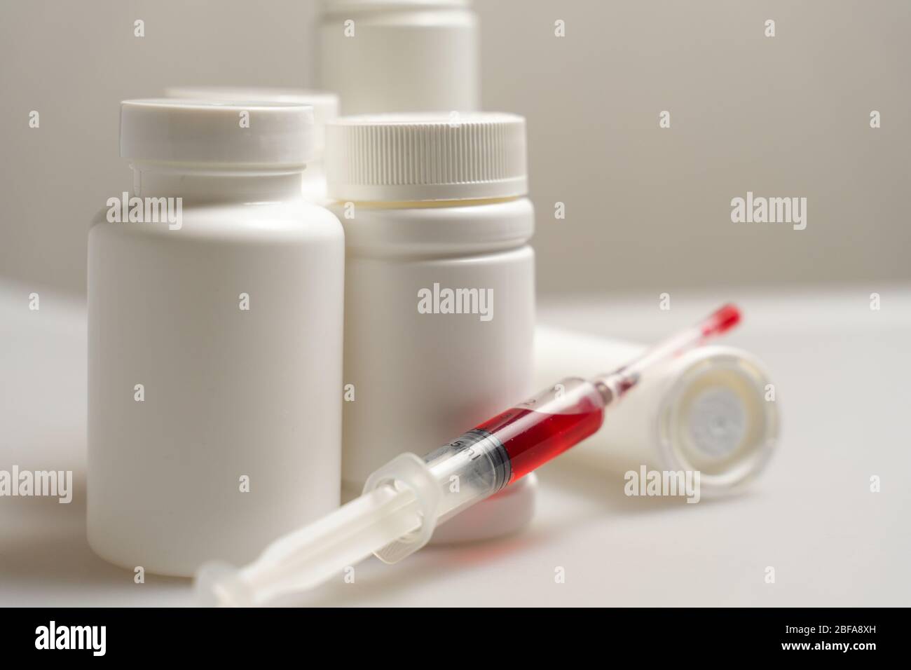 medical background. pill bottles without labels, syringe with red liquid. the need for vaccination in the modern world Stock Photo