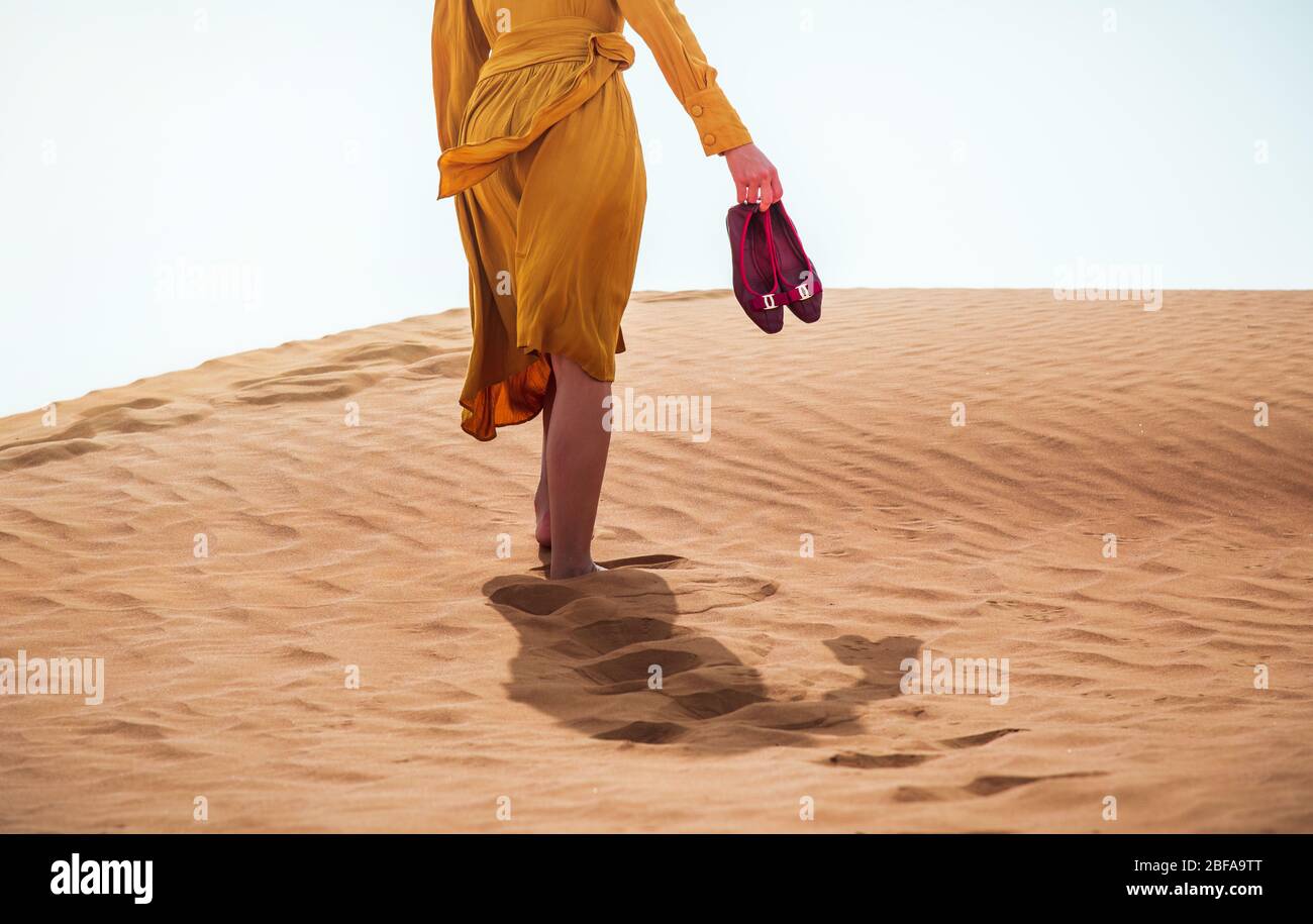 Woman walking in a desert on a sunny day rear low angle view Stock Photo