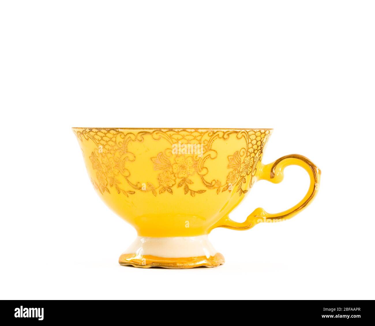 Single brightly coloured vintage tea cup with elegant floral design in gold. Retro, kitsch design. Isolated on white background. Stock Photo