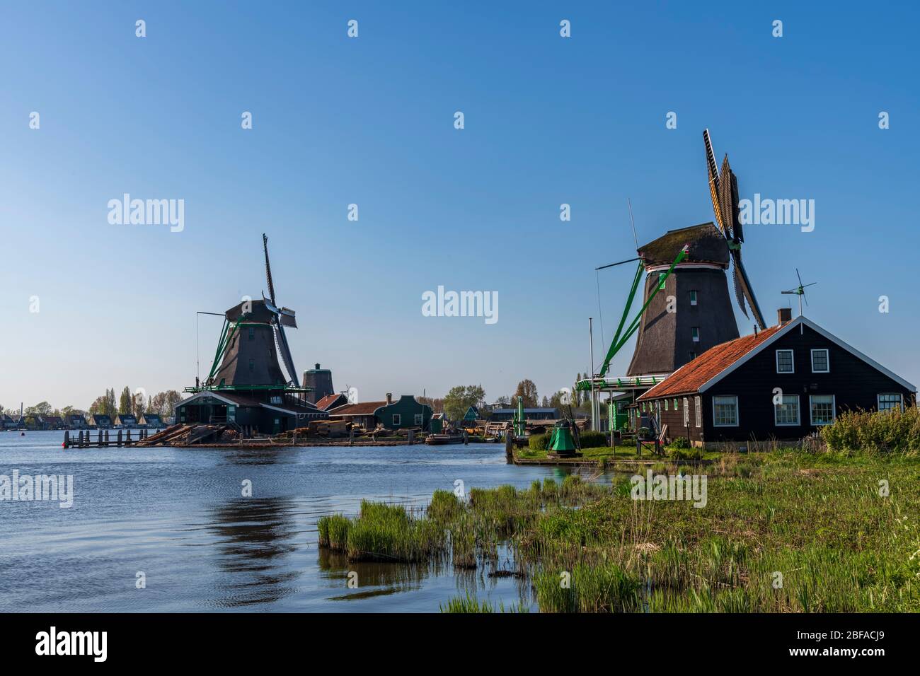 Aerial view of a old dutch traditional windmill on the rural countryside in The Netherlands with a dike, canals, bridge and fields. Stock Photo