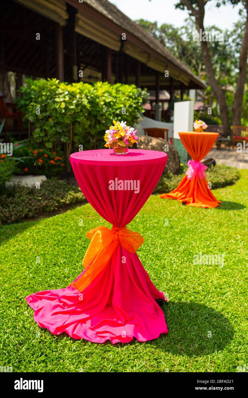 colorful beautiful orchid bouquet decor in glass vase setup on the wooden dinner table in India wedding venue reception. Stock Photo