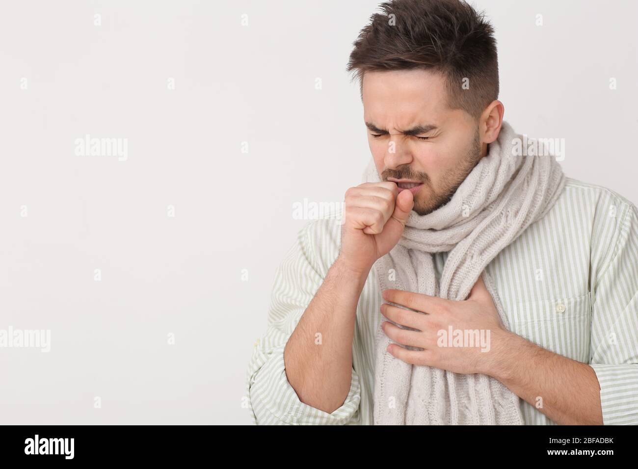 Coughing young man on light background Stock Photo Alamy