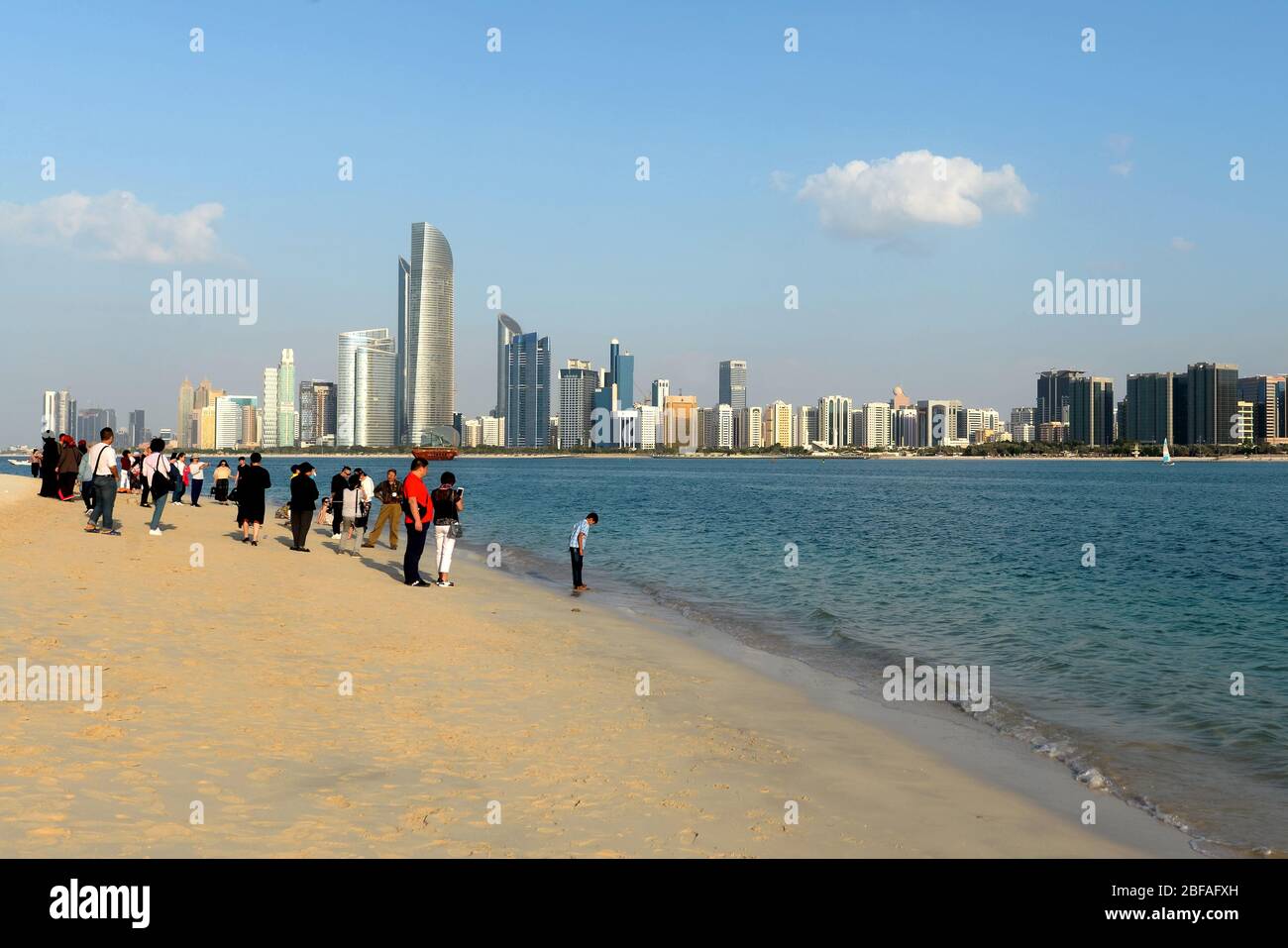Tourists posing for photos with Abu Dhabi skyline with multiple skyscrapers behind. Popular sightseeing place for travelers in United Arab Emirates. Stock Photo