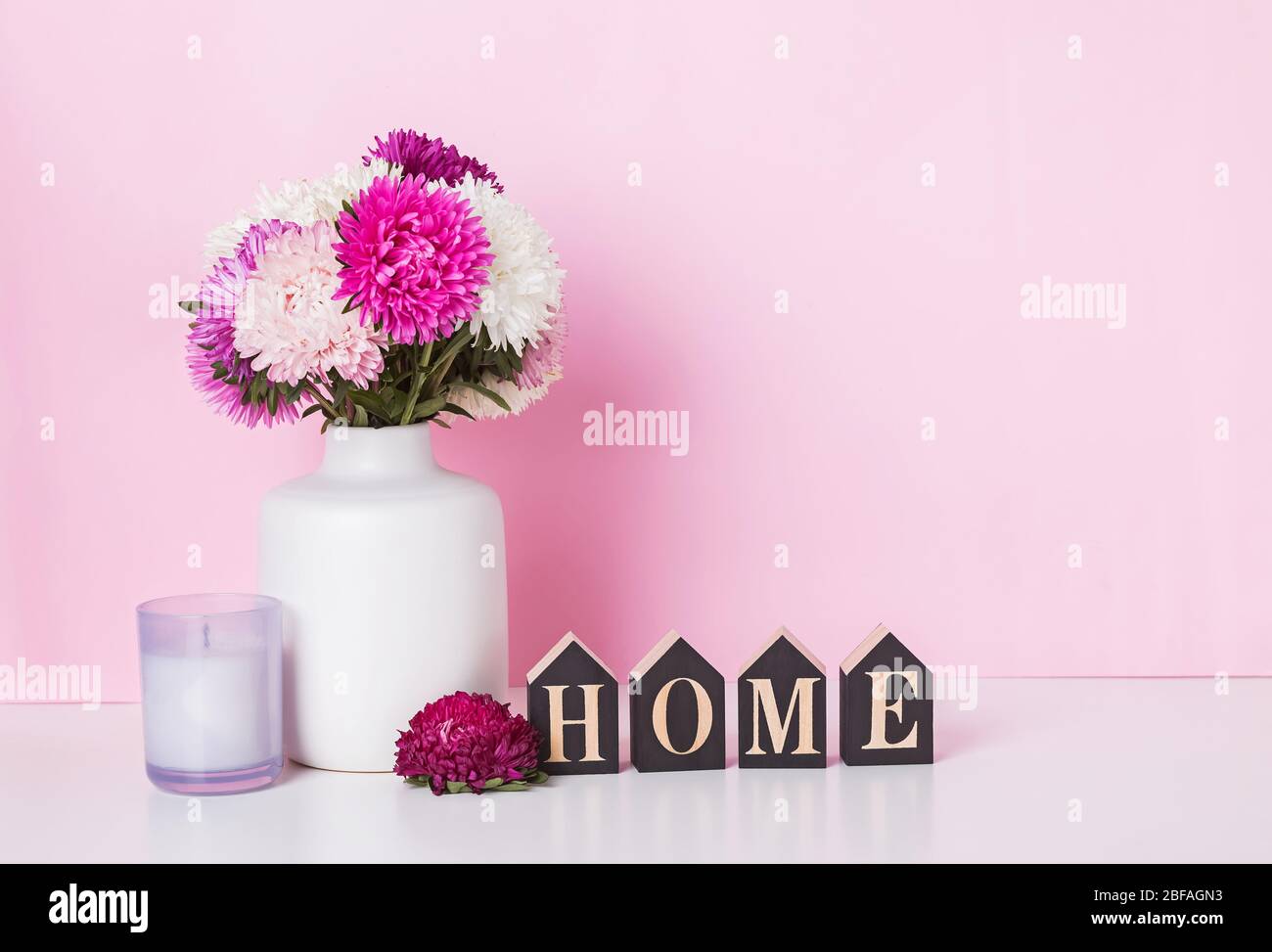 Still life composition with pink flowers and wooden letters home Stock Photo