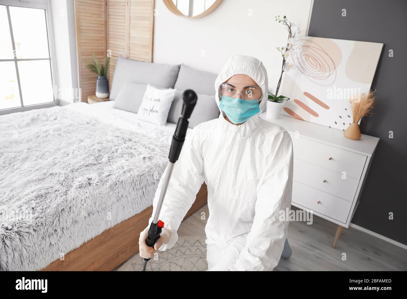 Worker in biohazard suit disinfecting house Stock Photo
