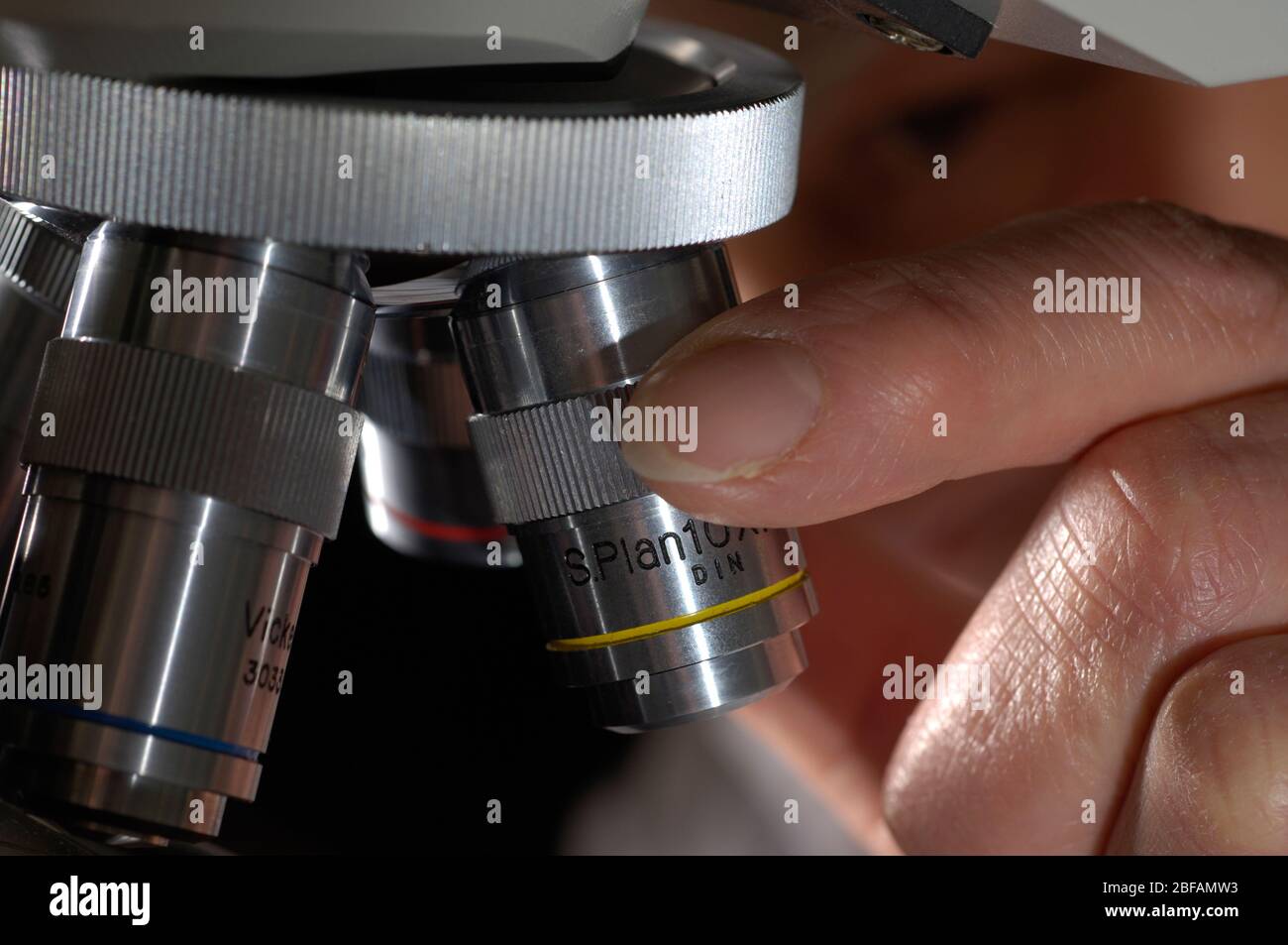 Science student adjusts a microscope to analyse biological samples ...