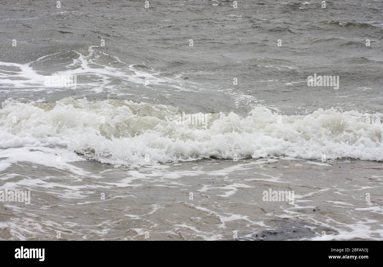 Waves with white crests inundate the sandy beachWellen mit weißen Schaumkronen überfluten den Sandstrand Stock Photo