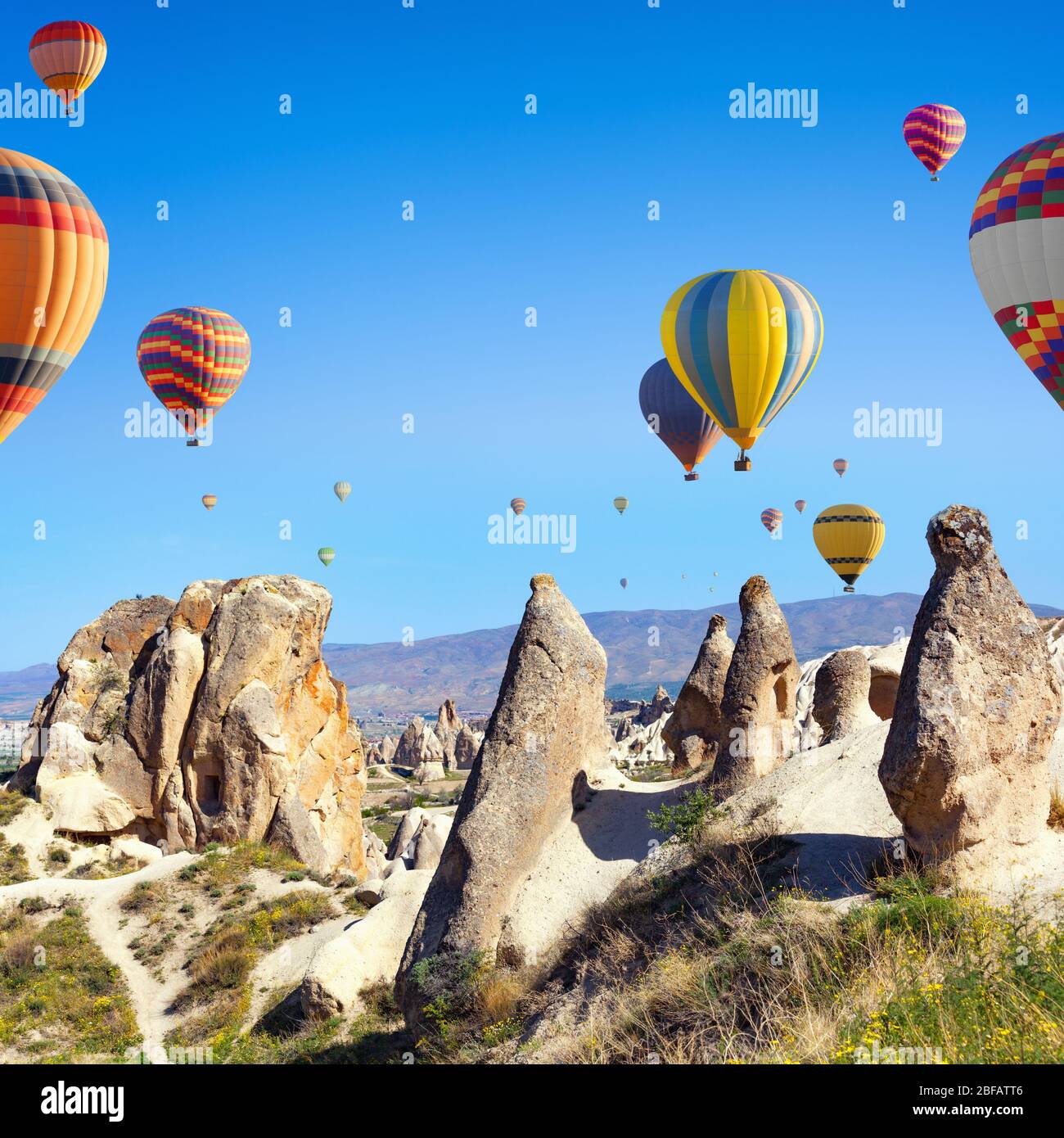 Sunny weather, limestone conical rocks near Goreme, Cappadocia, Turkey. Hot air ballooning is most popular attraction in Kapadokya. Stock Photo