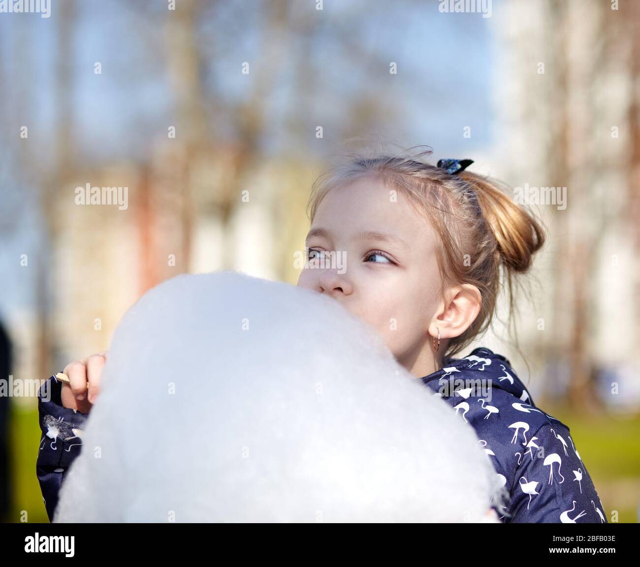 Cute little girl eating cotton candy. Happy childhood and children's