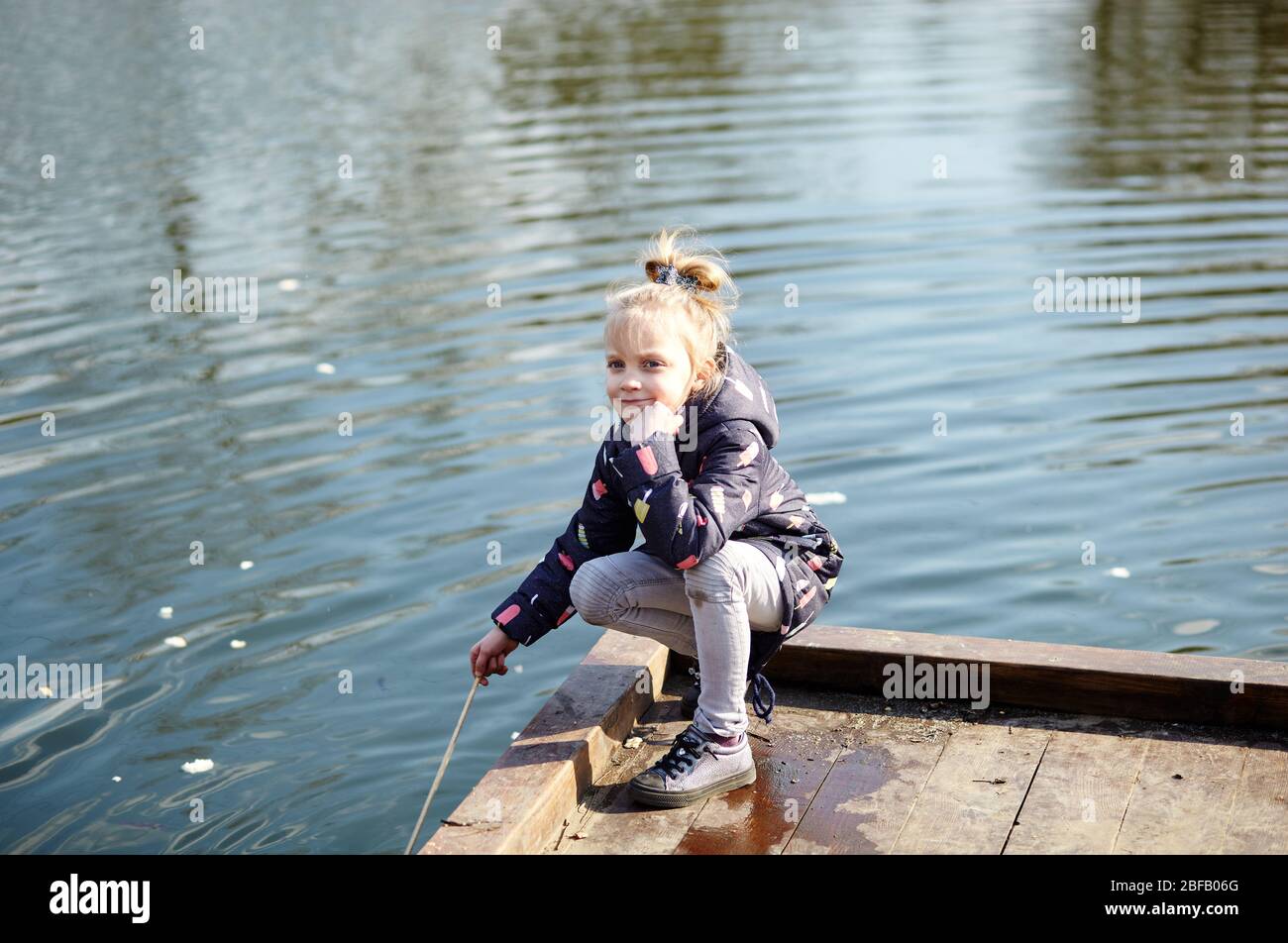 Cheerful child in blue jaket posing outdoors. Caucasian young girl enjoys a bright spring lifestyle Stock Photo