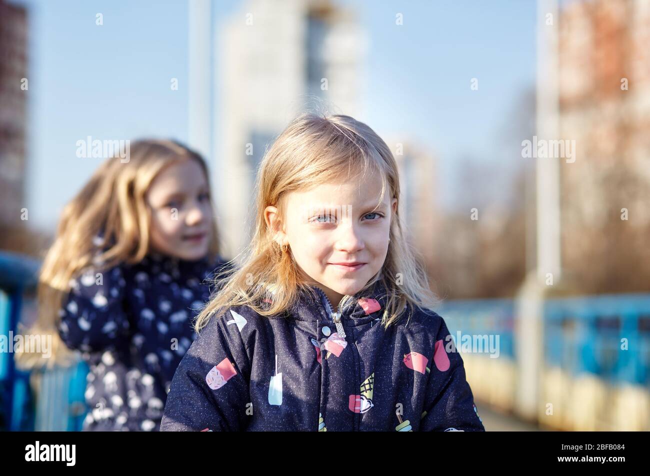 Adorable childs in blue jaket posing outdoors. Girls having fun together. Little baby girls in the park. Spring or autumn vacation Stock Photo